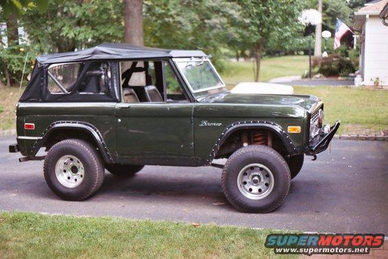Green 1976 Ford Bronco with a soft top, parked in a driveway