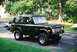 1976 Ford Bronco - A dark green 1976 Ford Bronco is parked on a paved driveway next to a silver sedan.