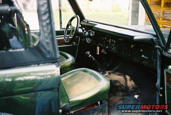 1976 Ford Bronco interior showing green vinyl seats, dashboard, steering wheel, and floor shifter