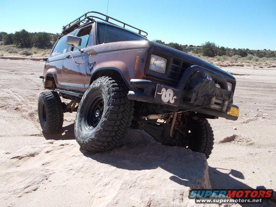 Brown Ford Bronco II with off-road tires on rocky terrain