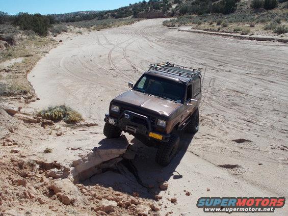 Brown 1986 Ford Bronco II navigating a rocky, sandy off-road trail