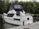 1985 Carver 326 Aft Cabin - A white Carver 350 boat is docked at a wooden pier, seen from the rear with a blue canvas covering the upper deck.