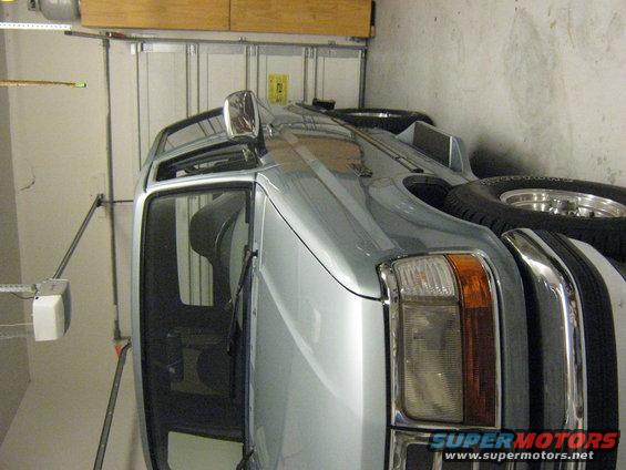 Silver SUV parked in garage, front quarter view, showing spare tire on rear