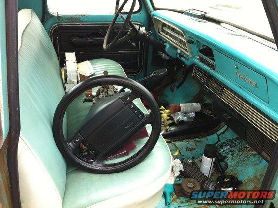 Interior of a turquoise truck, showing the dashboard, seats, and a steering wheel on the passenger seat