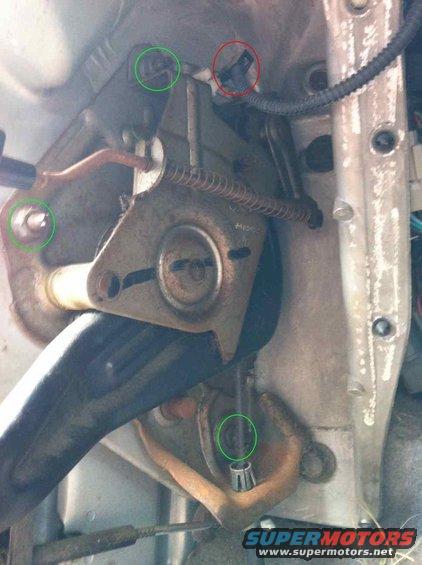 close-up of vehicle parking brake assembly with green and red circles highlighting components