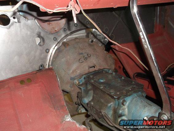 Transmission housing with 'C60' written on it, red painted metal panels, and wiring. A wrench is visible on the right
