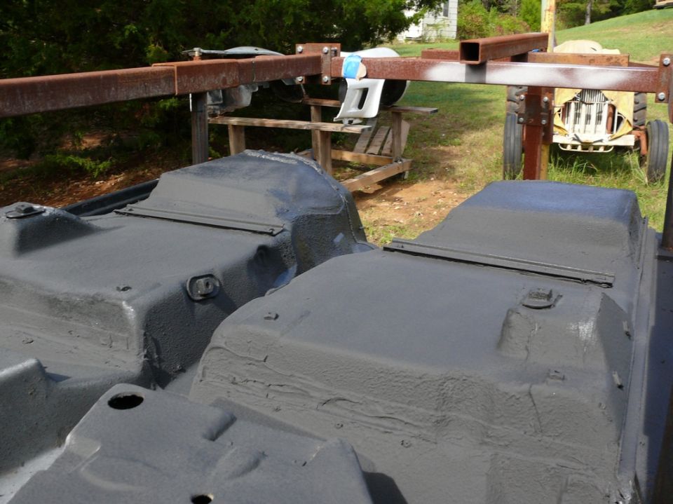 Two gray car underbodies on a metal stand outdoors