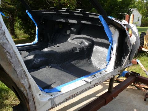 Car interior stripped down and painted black, with blue tape on door frames
