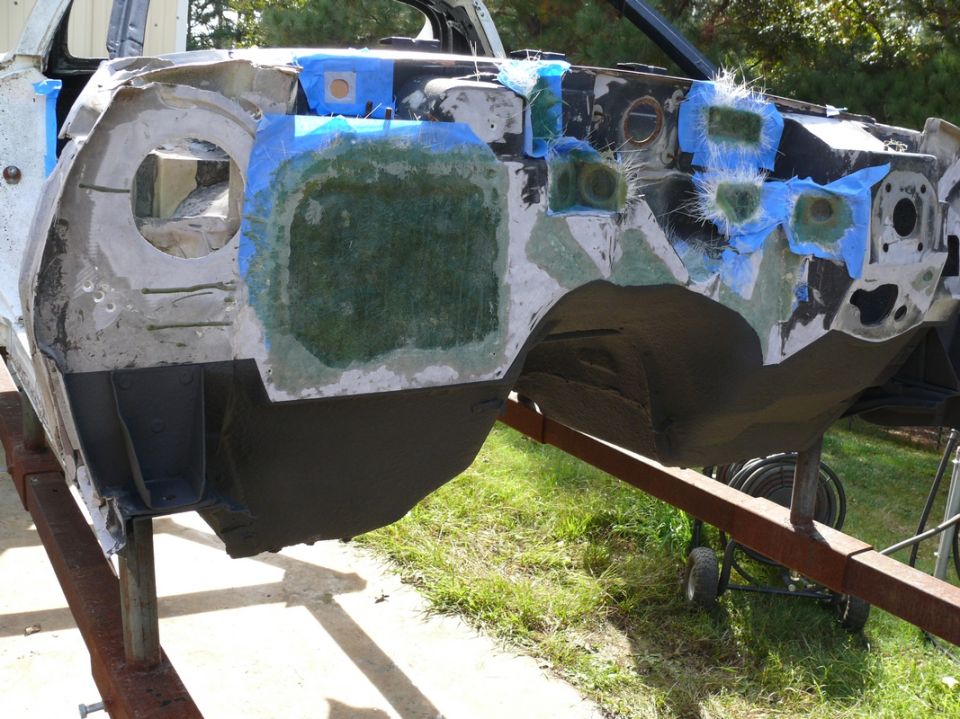 Car chassis on a stand, with fiberglass and blue tape on the firewall area