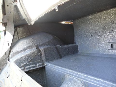 Interior of a car trunk, showing the wheel wells and floor coated in dark grey material