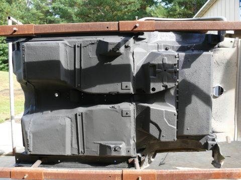 Gray car chassis underside on metal supports, viewed from below