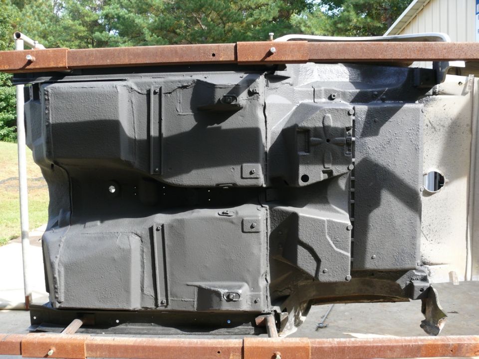 Gray car chassis underside on metal supports, viewed from below
