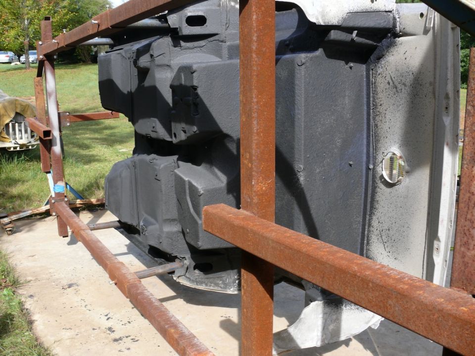 Underside of car chassis on stand, black undercoating visible