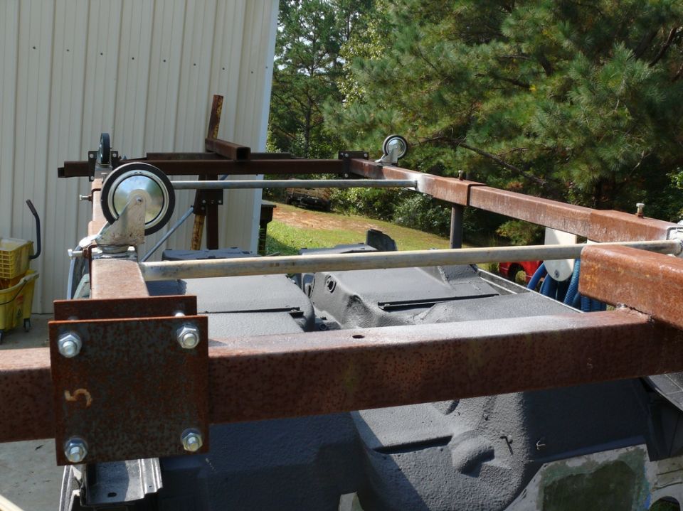 Metal frame with casters mounted over a dark surface, possibly a vehicle part