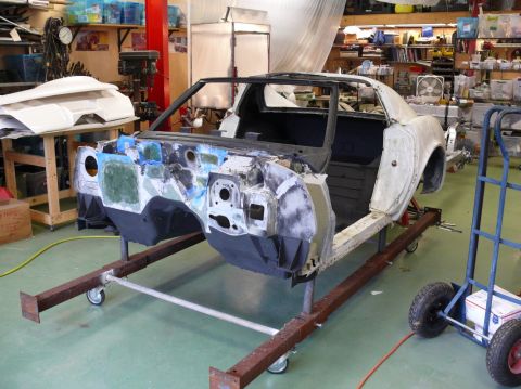 Car body on a stand in a workshop, looks like a 1976 Chevrolet Corvette