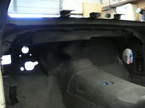 Interior of car with sound deadening applied to floor and firewall. Holes visible for pedals and steering colu