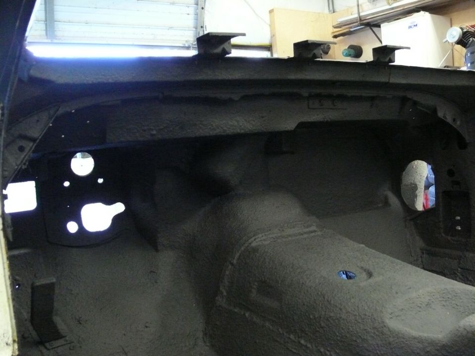 Interior of car with sound deadening applied to floor and firewall. Holes visible for pedals and steering column