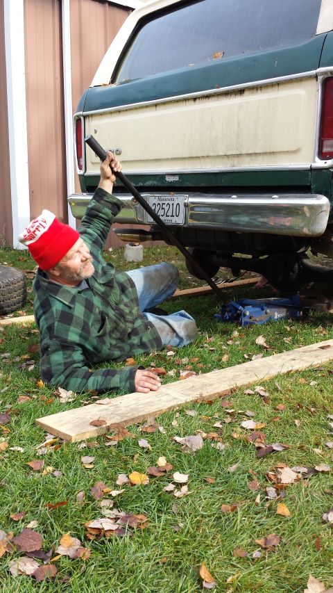 1978 Ford Bronco - A man works on the rear of a 1978 Ford Bronco, which is jacked up in a grassy yard.