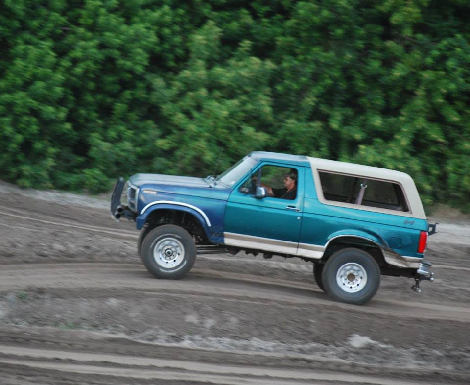 Teal and blue 1996 Ford Bronco driving on dirt track