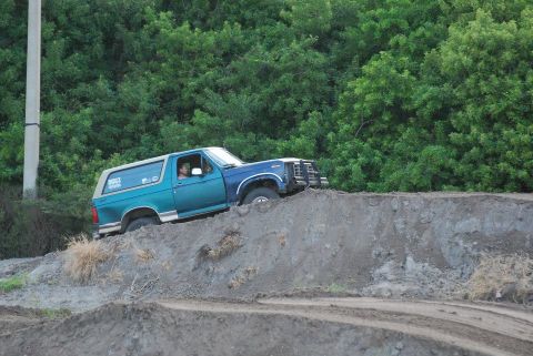 1996 Ford Bronco - A two-tone blue and teal Ford Bronco navigates a dirt track.