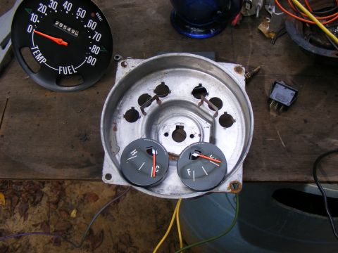 Car dashboard housing with temperature and fuel gauges, plus a separate speedometer/fuel gauge assembly
