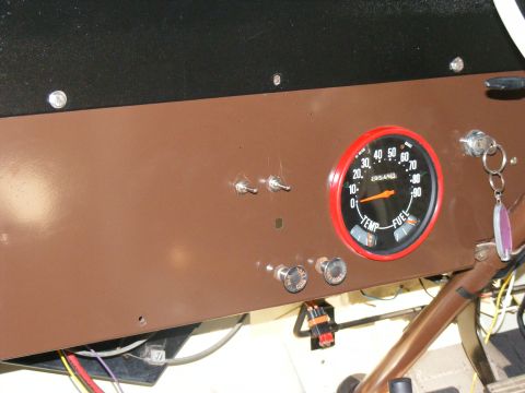 Brown dashboard with a round gauge showing fuel and temperature, two toggle switches, and two knobs