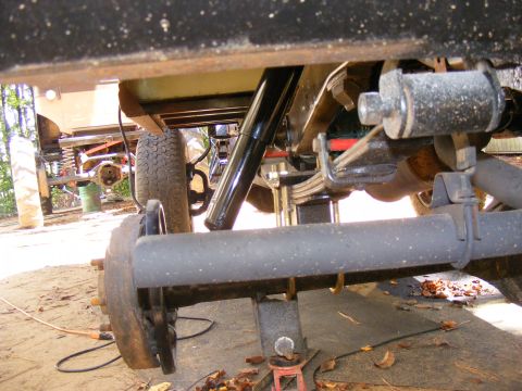 Underside view of a vehicle's rear axle, leaf springs, and shock absorber. A "SUPERMOTORS.NET" watermark is vi