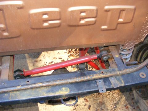 Close-up of tailgate with JEEP lettering. Undercarriage and suspension parts visible