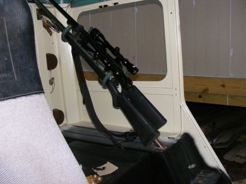 Two rifles with scopes mounted on a rack inside a cream-colored vehicle interior