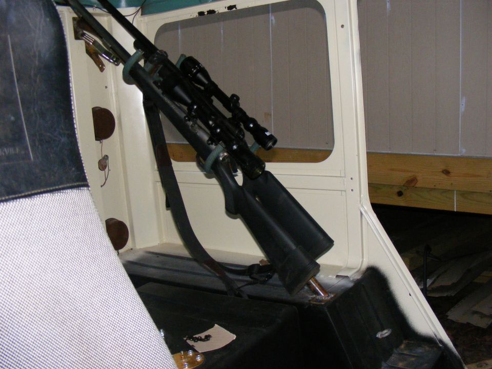 Two rifles with scopes mounted on a rack inside a cream-colored vehicle interior