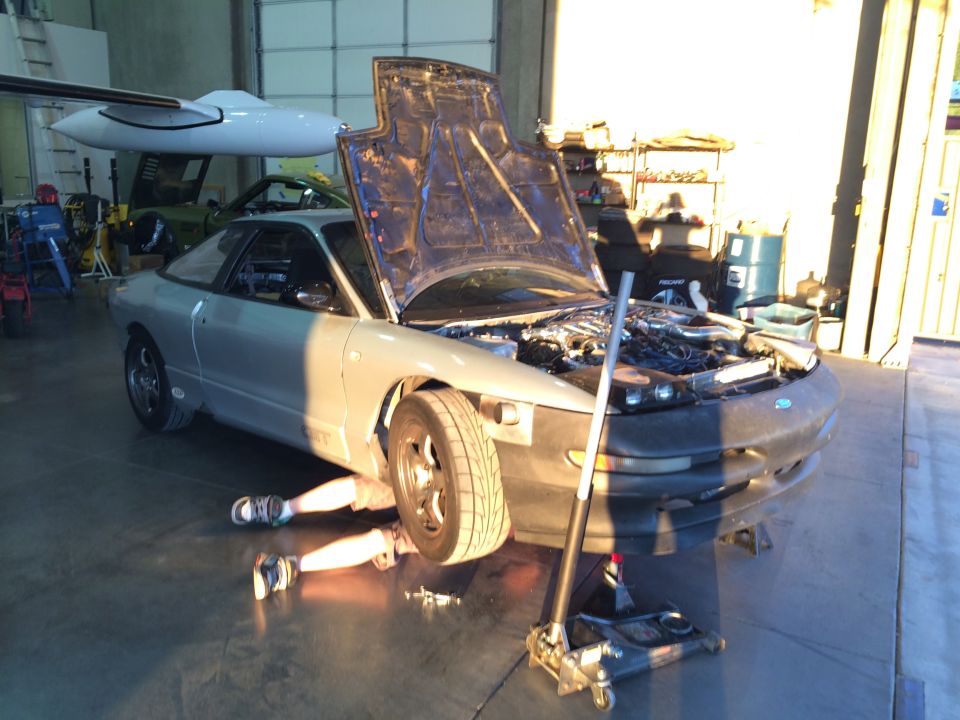 Silver coupe with hood open, person working underneath. 1995 Ford Probe