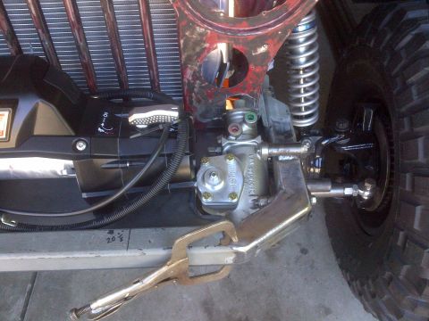 1985 Jeep CJ7 - Steering and suspension parts of a Jeep are visible, with a vise grip clamped to a metal bar.