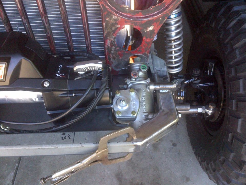 Close-up of Jeep steering box, tie rod, and suspension with a vise grip attached
