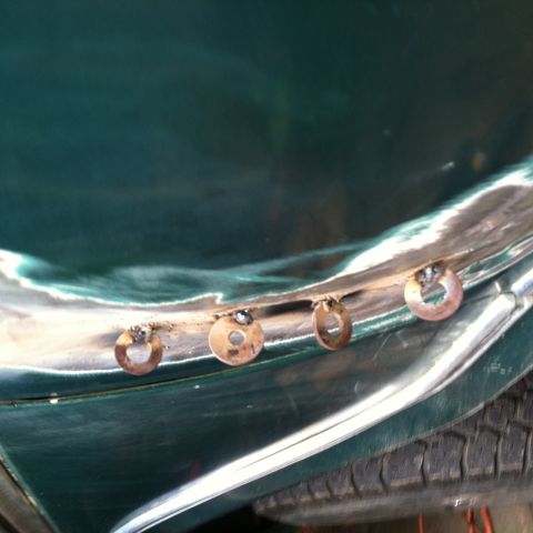 1978 Ford Bronco - Rivets are visible on the fender of a green vehicle undergoing restoration work.