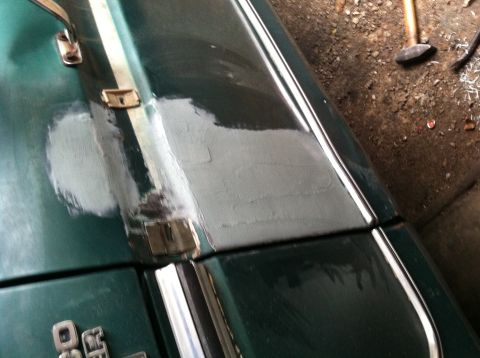 1978 Ford Bronco - A section of a green 1978 Ford Bronco hood shows body filler and chrome trim, indicating restoration work.