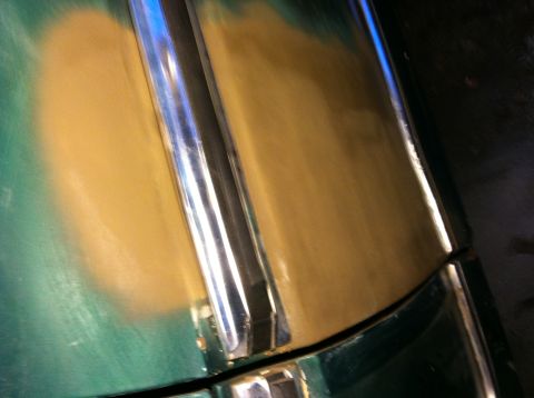 1978 Ford Bronco - Close-up of a vehicle's hood showing primer and a chrome trim piece, indicating restoration work.