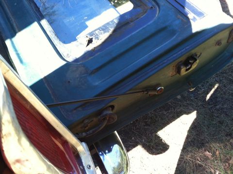1978 Ford Bronco - Close-up view of the tailgate latch mechanism and a support rod on a blue vehicle.