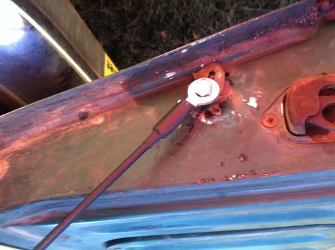 1978 Ford Bronco - Detail of a corroded hood hinge assembly, showing rust and wear on the metal components.
