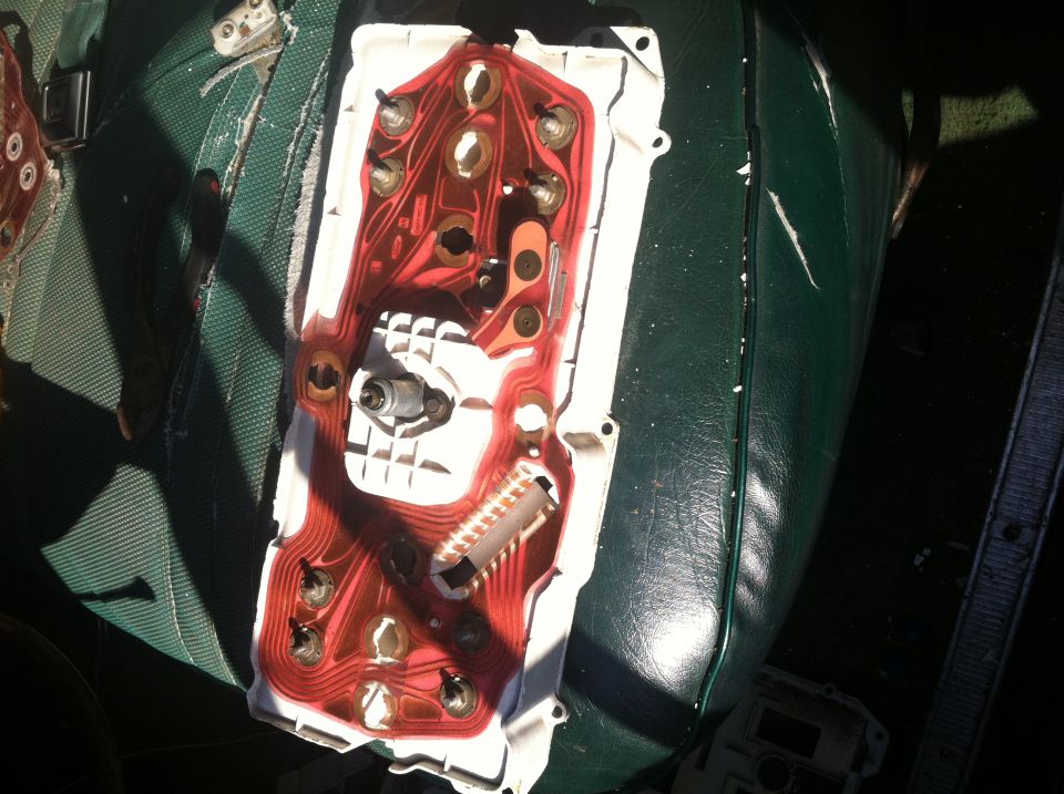 back of car dashboard gauge cluster with red circuit board and metal contacts