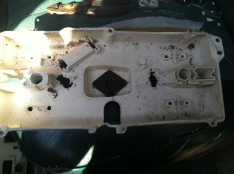 1978 Ford Bronco - The rear of a dusty and worn gauge cluster housing, showing its internal mounting structure and electrical connectors.