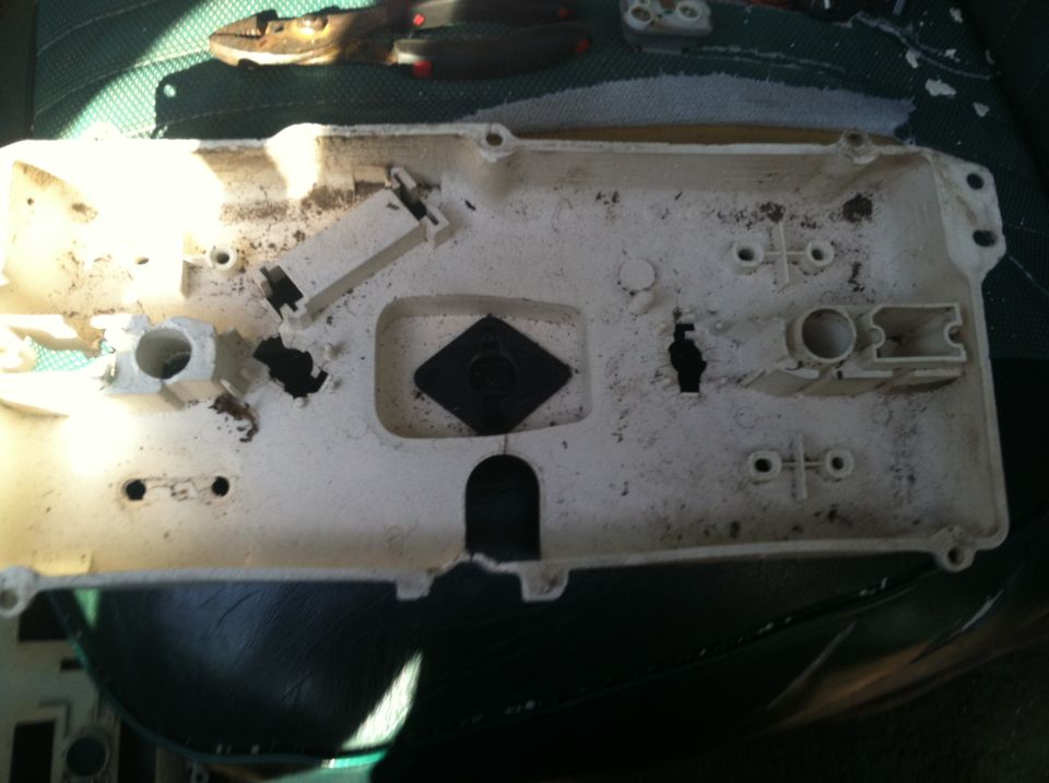 Back of a dirty gauge cluster housing with mounting points and connectors
