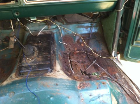 1978 Ford Bronco - Interior floor of a 1978 Ford Bronco shows significant rust damage and exposed wiring.