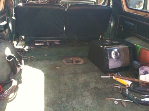 1978 Ford Bronco - The interior of a vehicle is shown, rear seats and a large black box with a projector lens.