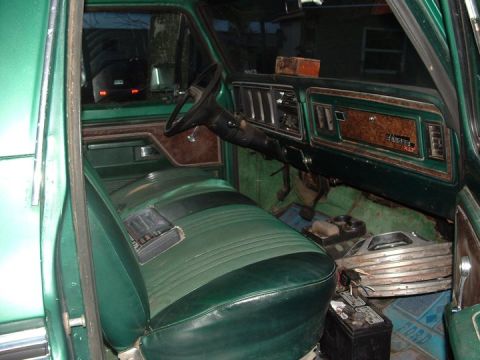 1978 Ford Bronco - The interior of a 1978 Ford Bronco shows its distinctive two-tone green seats and woodgrain dashboard trim.