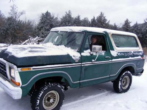 1978 Ford Bronco - A person sits in a snow-covered 1978 Ford Bronco parked in a winter landscape.