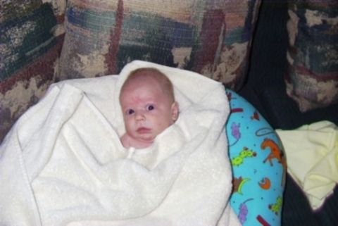 1995 Ford Bronco - A baby is swaddled in a white towel, resting on a couch with a patterned pillow.