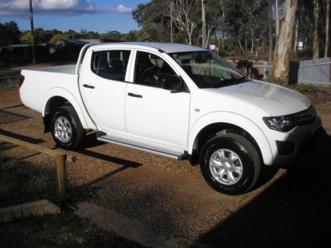 2013 Mitsubishi L200 - White pickup truck parked outdoors on a sunny day.