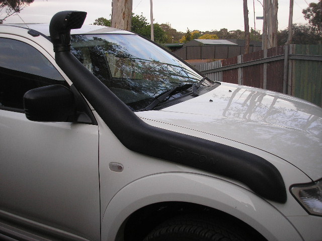 White Mitsubishi L200 pickup truck with a black snorkel installed on the passenger side. The vehicle is seen from the front quarter angle