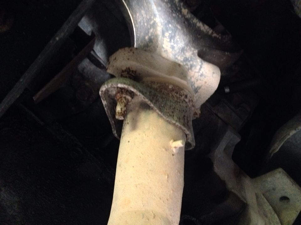 Close-up of a rusted exhaust pipe mount with a bolt