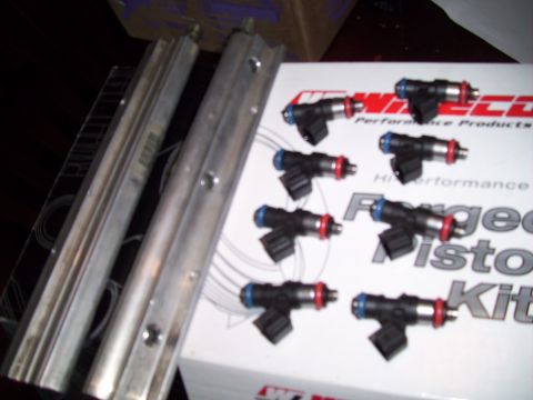 1995 Ford Probe - A set of fuel injectors and two fuel rails are laid out on a box for a forged piston kit.